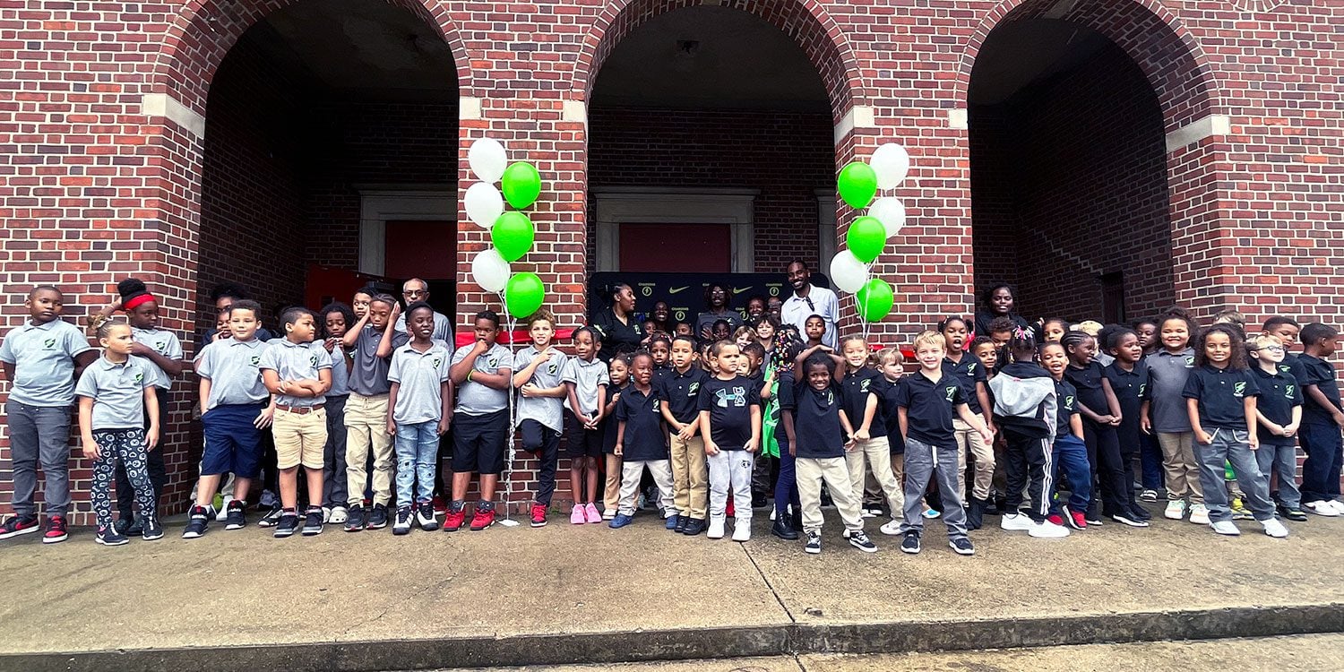 Group of children and adults posing outdoors with balloons.